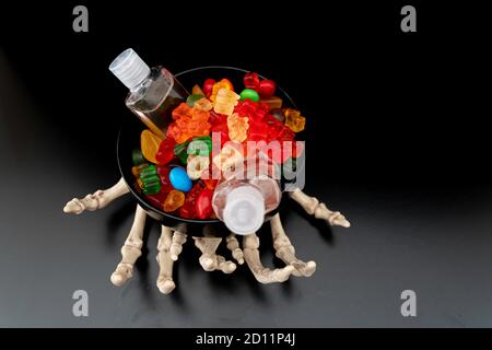 Skelett Kralle Hände mit Süßigkeiten und Hand Sanitizer - Halloween Konzept Stockfoto