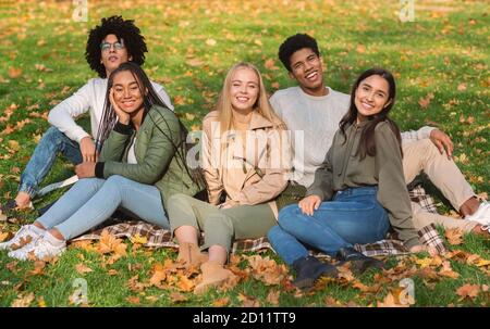 Unbeschwerte Teenager-Freunde sitzen auf dem Boden im öffentlichen Park Stockfoto