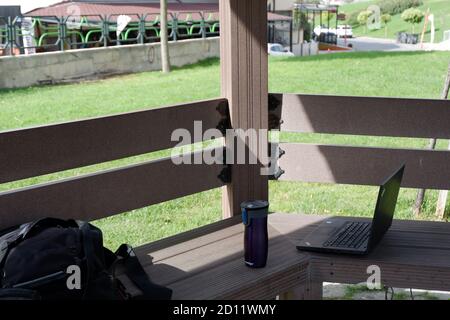 Arbeiten außerhalb des Büros an den Tagen der Quarantäne. Laptop, Tasche und Kaffee im Freien. Stockfoto