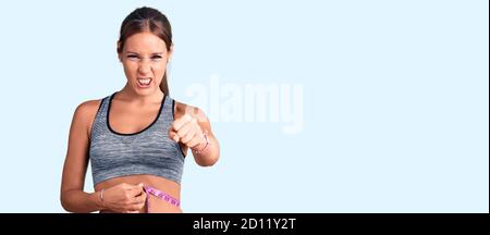 Junge schöne hispanische Frau trägt Sportkleidung mit Maßband verärgert und frustriert schreien vor Wut, schreien verrückt vor Wut und Hand rai Stockfoto