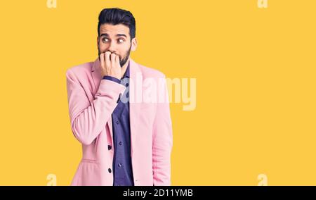 Junge gut aussehende Mann mit Bart trägt elegante Jacke, die gestresst und nervös mit den Händen auf den Mund beißen Nägel. Angst Problem. Stockfoto