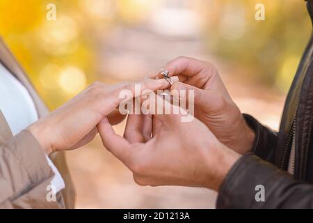 Mann, der Verlobungsring auf die Hand der Frau im Freien legt Stockfoto