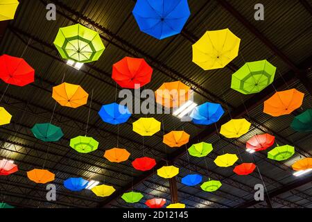 An der Metalldecke hängen farbenfrohe Regenschirme im Industriestil Gebäude Stockfoto