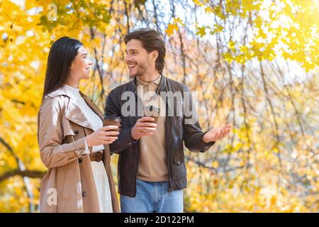 Glücklich verheiratetes Paar mit Tassen Kaffee, der durch den Wald spazierenging Stockfoto