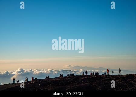 Maui, Hawaii. Besucher am Haleakala Krater im Haleakala Nationalpark beobachten den Sonnenuntergang über den Wolken. Stockfoto