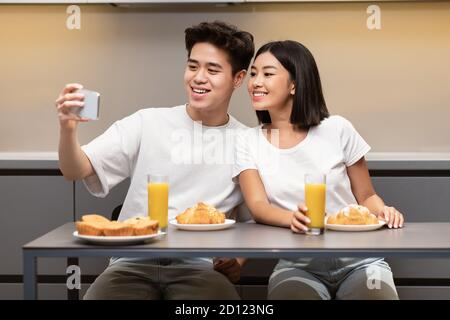 Koreanisch Ehemann Herstellung Selfie Mit Frau Während Frühstück In Der Küche Stockfoto