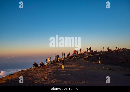 Maui, Hawaii. Touristen am Haleakala Krater im Haleakala Nationalpark beobachten den Sonnenuntergang über den Wolken. Stockfoto