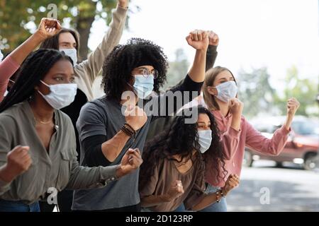 Junge Menschen in Schutzmasken, die an der Demonstration auf der Straße teilnehmen Stockfoto