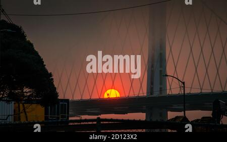 Aufgehende Sonne Feuerball über San Francisco Bay Brücke aus Waldbrände 2020 Stockfoto