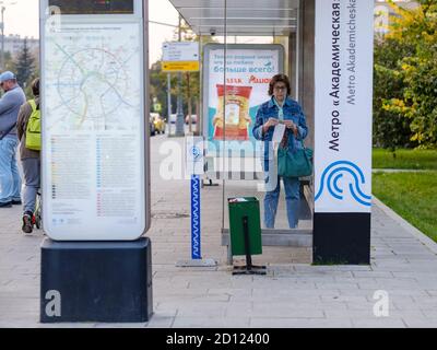 Moskau. Russland. September 25, 2020. Eine Erwachsene Frau steht in einem Pavillon der öffentlichen Verkehrsmittel, während sie auf einen Bus wartet. Eine Frau hält eine medizinische Maske in sich Stockfoto