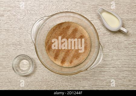 Die Stufe der Vorbereitung einer Charge Hefeteig. Auflösen von Hefe in einer transparenten tiefen Schüssel mit Milch. Stockfoto
