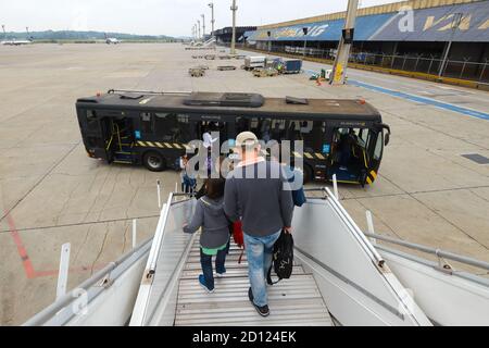 Passagiere steigen über eine Treppe am abgesetzten Stand am Flughafen Guarulhos ein. Ausschiffung durch Treppe. GRU Flughafenbus nach dem Absteigen. Stockfoto