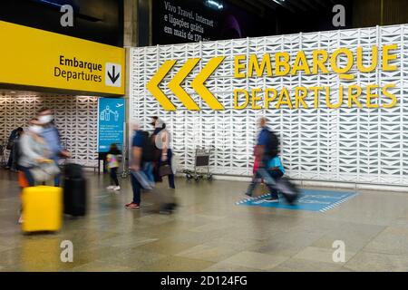 Schild für die Abflüge vom Flughafen Guarulhos am Inlandsterminal 2. Verschwommene Passagiere vor der Abflugsignalisierung am Flughafen GRU in Sao Paulo, Brasilien. Stockfoto