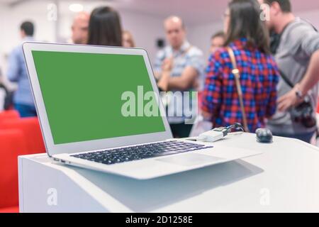 Laptop auf Business-Präsentationstisch mit verblurten Menschen im Hintergrund Bokeh. Stockfoto