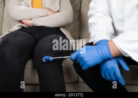 Männlicher Arzt untersucht den Kniereflex mit einem Testhammer Stockfoto