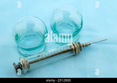 Glas Massage medizinische Gläser und eine alte Glasspritze auf Ein blaues medizinisches Blatt Stockfoto