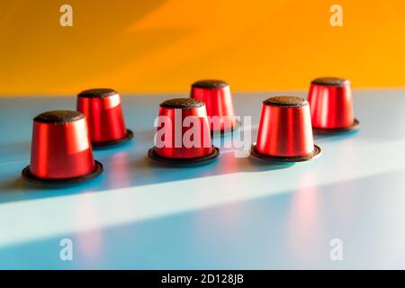 Eine Menge von roten Kapseln Kaffee offene Zusammensetzung auf blauem und orangefarbenem Hintergrund, flach legen. Kaffeekapsel für Lungo, Espresso.Copy Raum Stockfoto