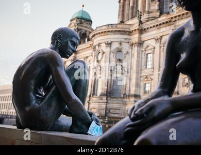 05. Oktober 2020, Berlin: Eine schmutzige Einwegmaske hängt an der Hand einer Figur aus der Skulptur "drei Mädchen und ein Junge" von Wilfried Fitzenreiter an der Spree. Foto: Annette Riedl/dpa Stockfoto