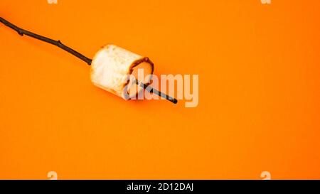 Gegrilltes Marshmallow auf Stick auf gelbem Hintergrund mit Kopierplatz. Herbst Camping Spaß Stockfoto