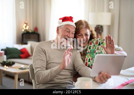 Vorderansicht des älteren Ehepaares zuhause zu Weihnachten, mit Videoanruf mit der Familie. Stockfoto
