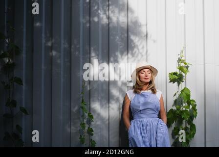 Porträt der reifen Frau im Freien im Garten stehend, entspannend. Speicherplatz kopieren. Stockfoto