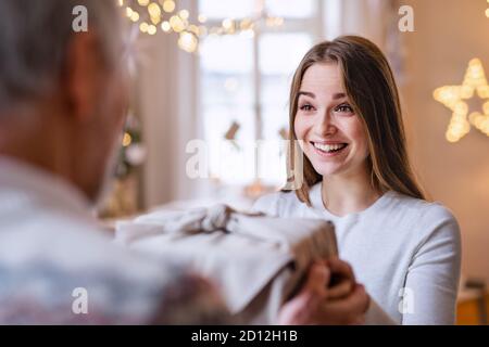 Junge Frau erhält Geschenk von nicht erkennbaren Großvater drinnen zu Hause zu Weihnachten. Stockfoto