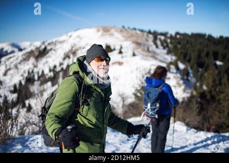 Seniorenpaar mit nordic Walking Stöcken Wandern in schneebedeckter Winternatur. Stockfoto