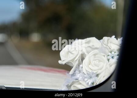 Hochzeit Dekoration auf dem Glas eines Autos, zarte Stoff Bouquet von weißen Rosen. Stockfoto