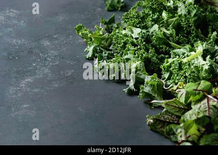 Grüner Salat Mix für Salat oder Smoothie mit Grünkohl, junge Rote Bete Blätter, Triebe, über dunkle Textur Oberfläche. Kopieren Sie Platz. Essen Hintergrund. Stockfoto