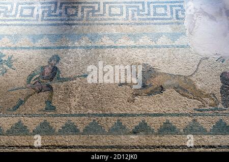 Haus von Dionysos, Paphos: Das Jagdmosaik zeigt einen Mann mit einem Speer, der einen aufladendem Löwen jagt Stockfoto