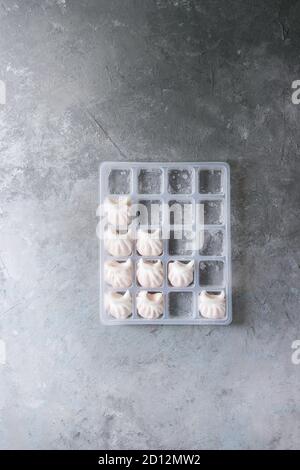 Tiefgekühlte Fertiggerichte asiatischen potstickers Klöße zu kochen von Garnelen in Kunststoffbox über grau Textur Hintergrund gefüllt. Ansicht von oben, Platz. Halbzeug Stockfoto