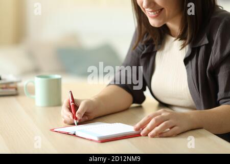 Nahaufnahme einer glücklichen Frau, die auf der Tagesordnung auf einem Schreibtisch stand Zu Hause Stockfoto