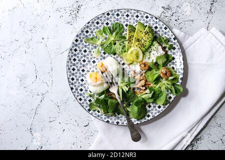 Vegetarische Sandwiches mit Avocado, Ricotta, pochiertes Ei, Spinat auf Vollkorn Toast Brot auf Keramikteller mit textilen Serviette über weißem Marmor ba Stockfoto