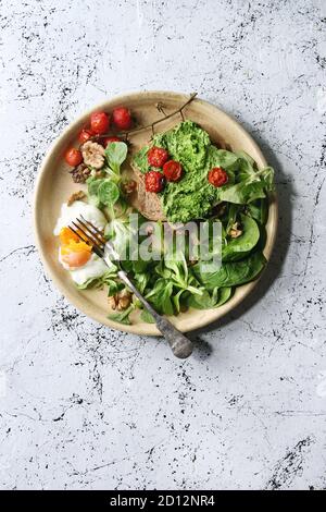 Die Hände des Mannes halten rohe ungekochte schwarze angus Rindfleisch Tomahawk Steaks Auf Knochen mit Salz und Pfeffer auf runder Holzschiefer Schneidebrett über dunklem Holz p Stockfoto