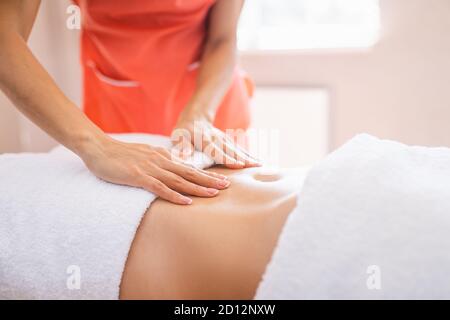 Frau hat eine Bauchmassage im hellen Verfahrensraum. Anti-Cellulite-Massage, Diastase. Stockfoto