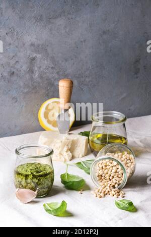 Traditionelle Basilikum Pesto in Glas Glas mit Zutaten oben frisches Basilikum, Olivenöl, Parmesan, Knoblauch, Pinienkernen, lemon am Küchentisch w Stockfoto