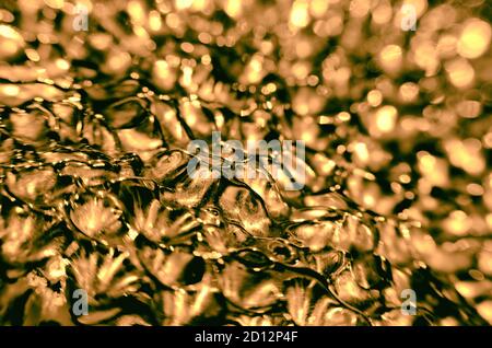 Gewelltes goldenes abstraktes Glas Oberfläche Hintergrund mit glänzendem Bokeh Stockfoto