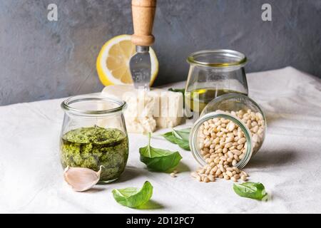 Traditionelle Basilikum Pesto in Glas Glas mit Zutaten oben frisches Basilikum, Olivenöl, Parmesan, Knoblauch, Pinienkernen, lemon am Küchentisch w Stockfoto