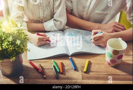 Kind und Erwachsener malen ein Malbuch. Neuer Trend zur Stressabbau. Konzept Achtsamkeit, Entspannung. Stockfoto