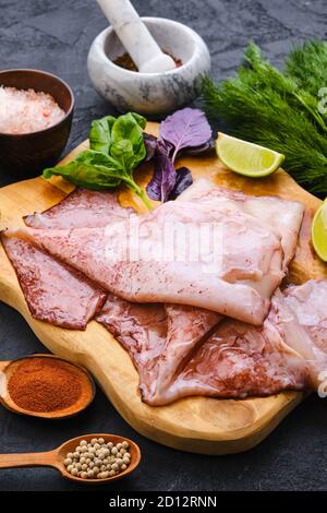 Roher frischer, ungeschälter Tintenfisch auf Holzschneidebrett mit Gewürzen Und Kräuter Stockfoto