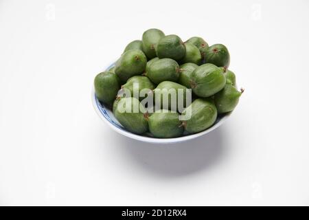 Kiwi-Beeren (Actinidia arguta) in einer kleinen weißen Schüssel auf einer weißen Arbeitsplatte. Stockfoto