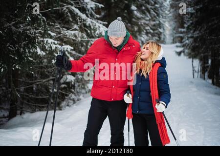 Ein Ehepaar genießt sich gegenseitig, den Geruch, die Stille und die Einheit an einem frostigen Wintermorgen auf Skiern in einem Fichtenwald. Stockfoto