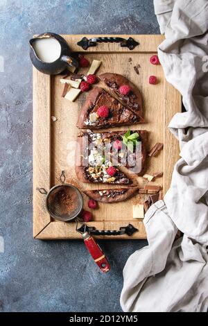 Hausgemachten süßen Dessert Schokolade Pizza mit verschiedenen Schokoladen, Himbeeren und Minze serviert auf einem Tablett mit Tuch und Zutaten oben über Blu Stockfoto