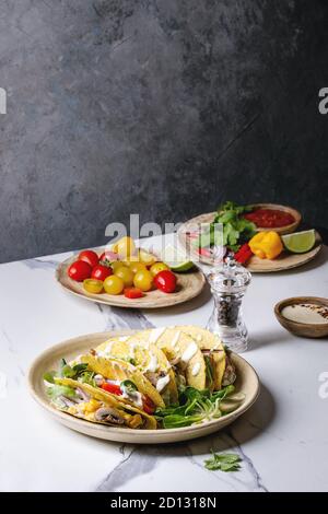 Auswahl an vegetarischen Mais Tacos mit Gemüse, Salat, Chili Pfeffer auf Keramikteller mit Tomaten und Sahne Saucen mit Zutaten serviert abov Stockfoto