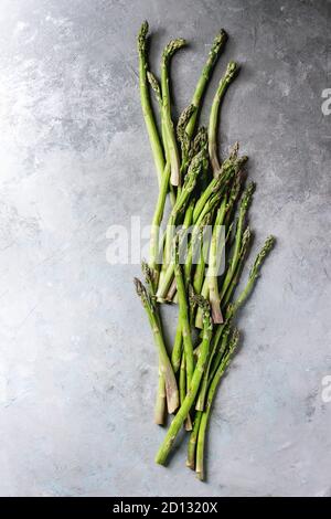 Roh ungekocht organischen grünen Spargel in der Zeile über grau Textur Hintergrund. Ansicht von oben, kopieren. Stockfoto