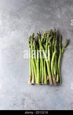 Roh ungekocht organischen grünen Spargel in der Zeile über grau Textur Hintergrund. Ansicht von oben, kopieren. Stockfoto