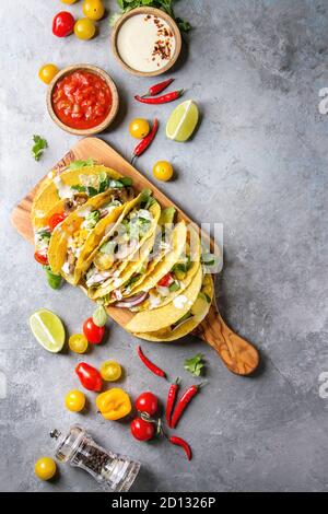 Auswahl an vegetarischen Mais Tacos mit Gemüse, Salat, Chili Pfeffer auf olivenholz Brett mit Tomaten serviert, Sahne Saucen mit Zutaten abov Stockfoto