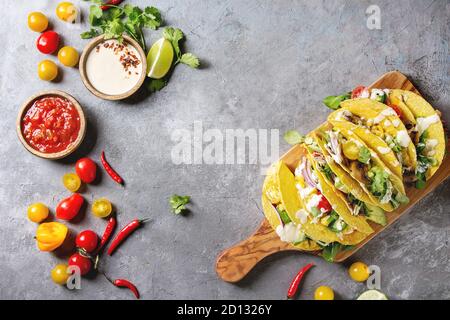 Auswahl an vegetarischen Mais Tacos mit Gemüse, Salat, Chili Pfeffer auf olivenholz Brett mit Tomaten serviert, Sahne Saucen mit Zutaten abov Stockfoto