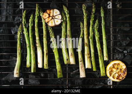 Gegrilltes Gemüse grüner Spargel, Knoblauch, Zitrone auf BBQ Grill Rack über Kohle. Ansicht von oben, Platz. Stockfoto