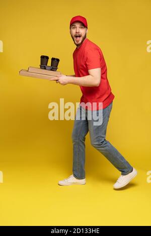Lieferung Mann in roter Mütze, T-Shirt Uniform isoliert auf gelbem Hintergrund Studio Stockfoto